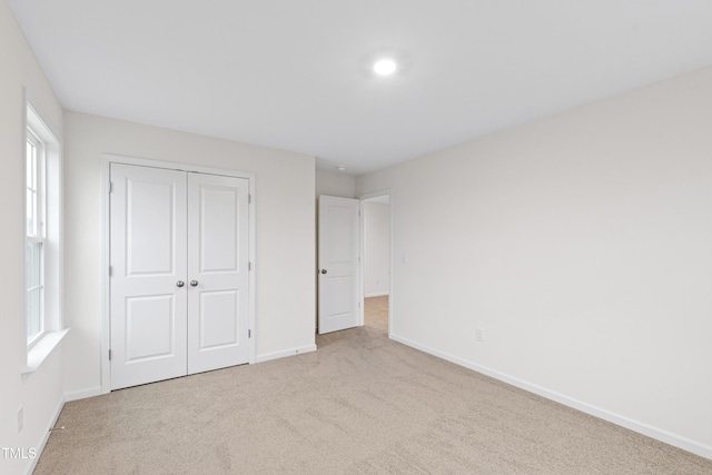 unfurnished bedroom featuring light carpet and a closet