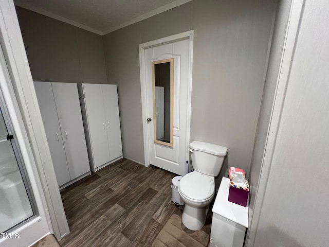 bathroom with wood-type flooring, crown molding, vanity, and toilet