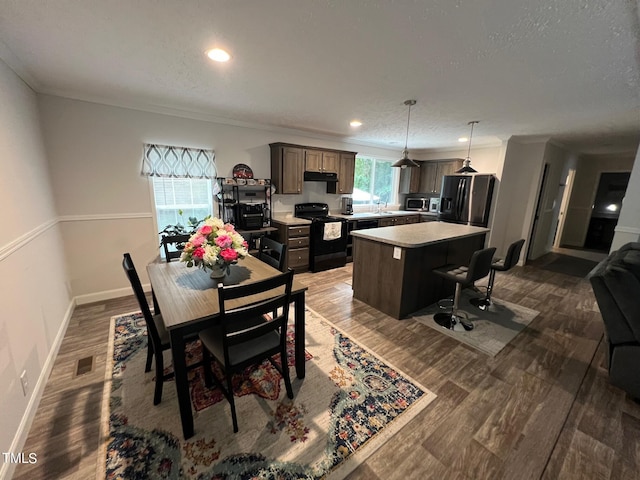 dining space featuring a textured ceiling, wood-type flooring, and crown molding