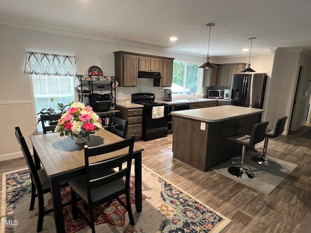 kitchen featuring a kitchen island, light hardwood / wood-style flooring, stainless steel appliances, decorative light fixtures, and ornamental molding