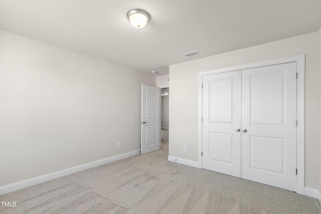 unfurnished bedroom with light carpet and a closet