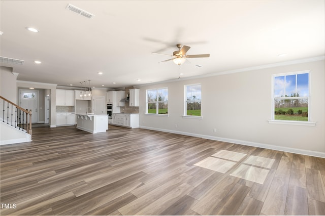 unfurnished living room with hardwood / wood-style flooring, ceiling fan, ornamental molding, and sink