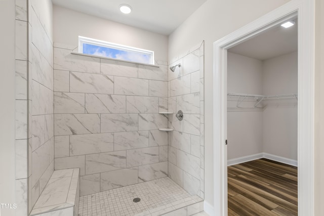 bathroom featuring a tile shower and wood-type flooring