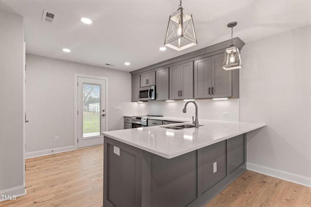 kitchen with pendant lighting, gray cabinetry, sink, and stainless steel appliances