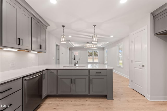 kitchen featuring sink, light hardwood / wood-style flooring, stainless steel dishwasher, kitchen peninsula, and gray cabinets