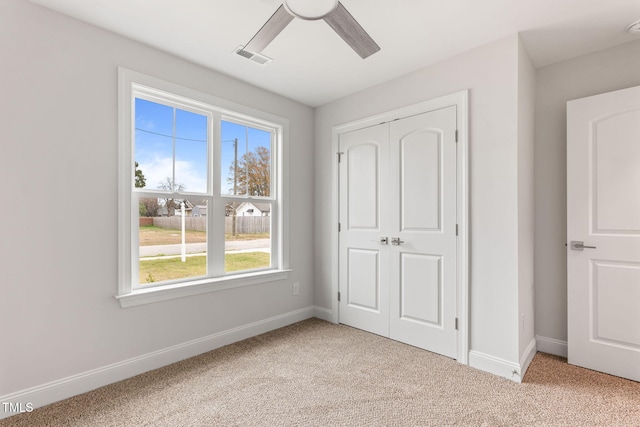 unfurnished bedroom featuring ceiling fan, a closet, and light carpet