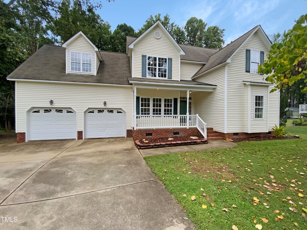 view of front of home featuring covered porch, a front yard, and a garage