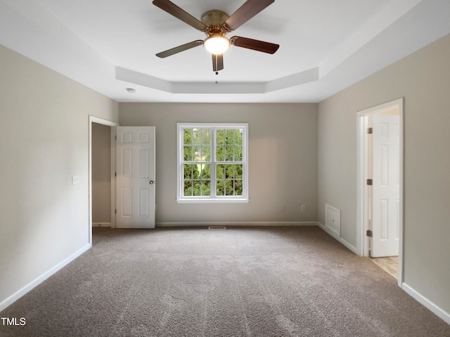 carpeted spare room featuring ceiling fan and a tray ceiling