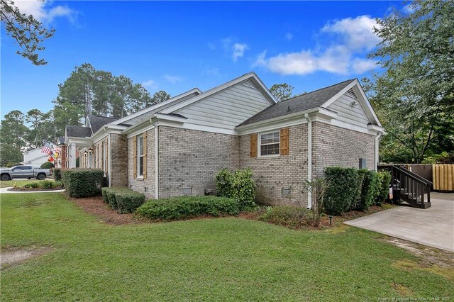 view of home's exterior featuring crawl space, brick siding, a yard, and concrete driveway