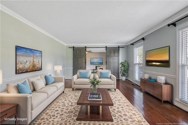 living room with ornamental molding, wood finished floors, and a barn door