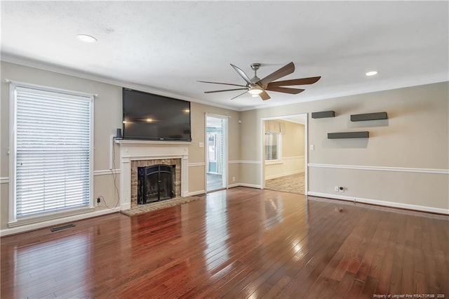 unfurnished living room with visible vents, ornamental molding, wood finished floors, a healthy amount of sunlight, and a brick fireplace