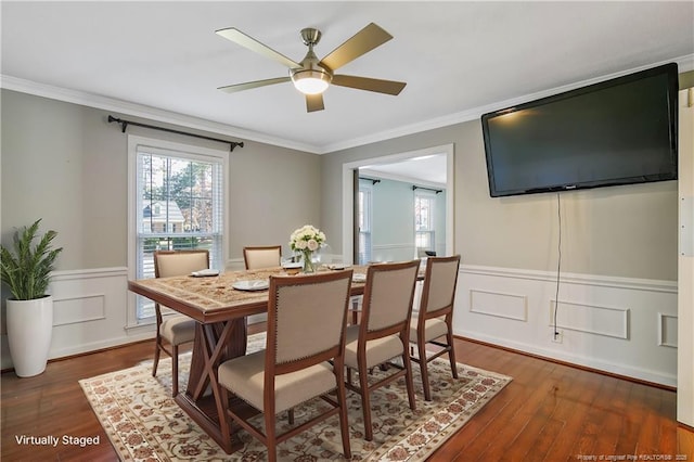 dining room featuring dark wood-style floors, a wainscoted wall, crown molding, and ceiling fan