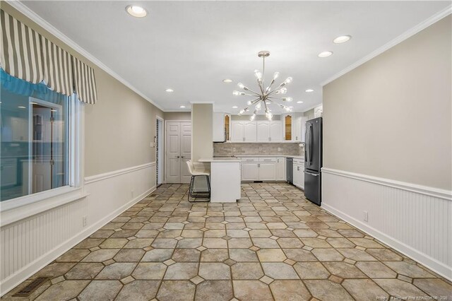 kitchen featuring a breakfast bar area, a wainscoted wall, stainless steel appliances, white cabinetry, and light countertops