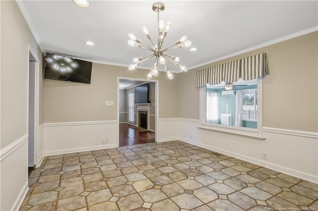 unfurnished room featuring wainscoting, crown molding, a fireplace, a chandelier, and recessed lighting