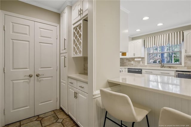 kitchen featuring light countertops, tasteful backsplash, a breakfast bar area, and white cabinetry