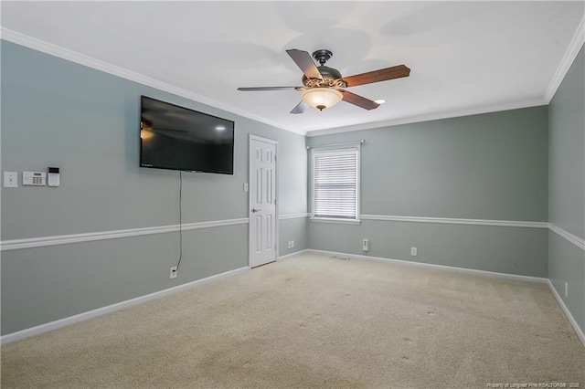 spare room featuring carpet floors, a ceiling fan, baseboards, and crown molding