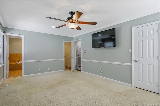 unfurnished bedroom with ensuite bathroom, light colored carpet, a ceiling fan, baseboards, and ornamental molding