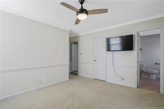 unfurnished bedroom featuring ornamental molding, a ceiling fan, light carpet, ensuite bath, and baseboards