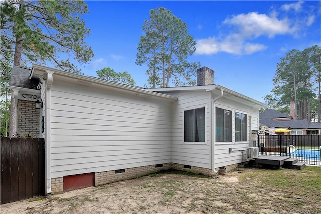 view of side of property with crawl space, a chimney, fence, and a fenced in pool