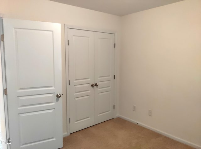 unfurnished bedroom with light carpet and a closet