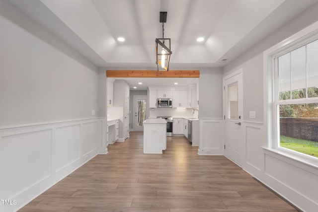 kitchen with sink, stainless steel appliances, a kitchen island, pendant lighting, and white cabinets