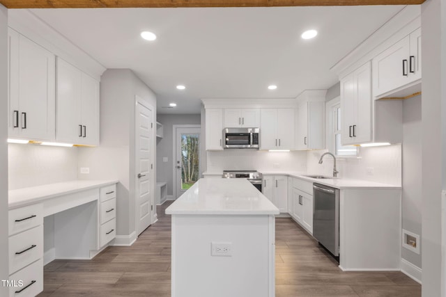 kitchen featuring sink, a center island, appliances with stainless steel finishes, white cabinets, and hardwood / wood-style flooring