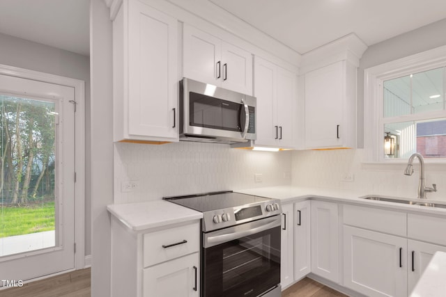 kitchen featuring white cabinets, stainless steel appliances, light hardwood / wood-style floors, and sink