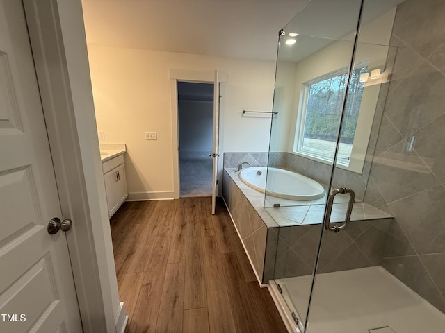 bathroom featuring wood-type flooring, shower with separate bathtub, and vanity