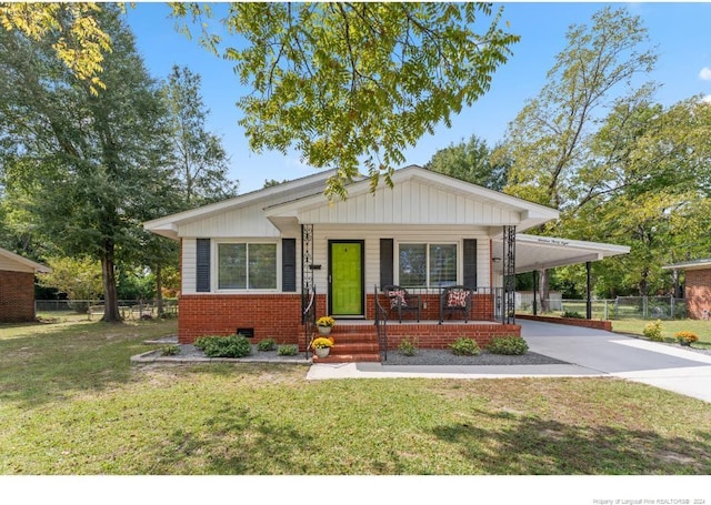 view of front of property with covered porch, a front yard, and a carport