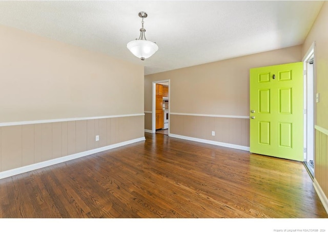 empty room with dark hardwood / wood-style floors and a textured ceiling