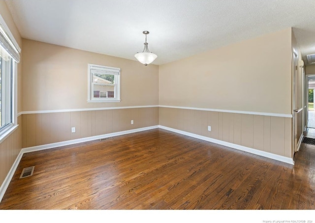 spare room with a textured ceiling and dark hardwood / wood-style floors