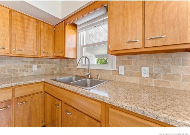 kitchen with tasteful backsplash, sink, and light stone counters