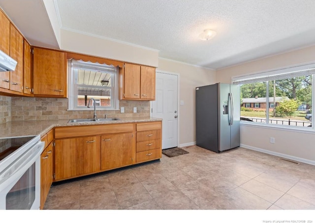 kitchen featuring white range oven, stainless steel fridge, a textured ceiling, decorative backsplash, and sink