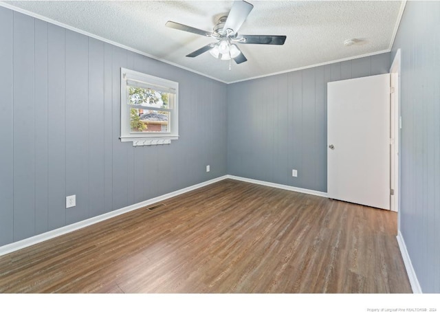 unfurnished room featuring wood walls, hardwood / wood-style flooring, ceiling fan, and ornamental molding