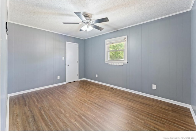 unfurnished room with hardwood / wood-style floors, wood walls, ceiling fan, and crown molding