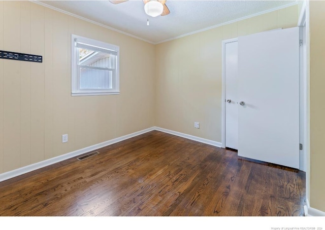 empty room featuring dark wood-type flooring, ceiling fan, and crown molding