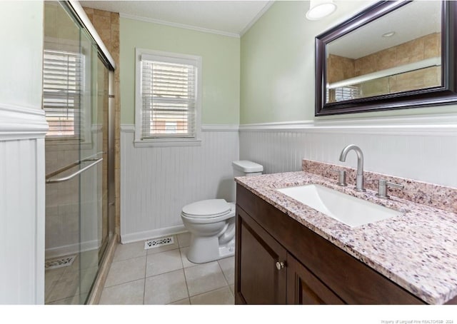 bathroom featuring toilet, tile patterned flooring, vanity, crown molding, and a shower with shower door