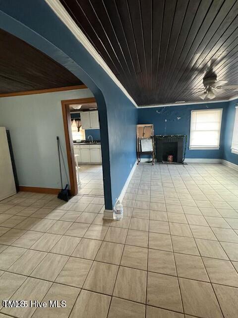 unfurnished living room featuring ceiling fan, wooden ceiling, ornamental molding, and light tile patterned floors