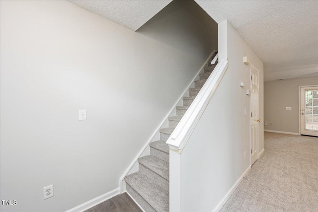 staircase featuring a textured ceiling and carpet flooring