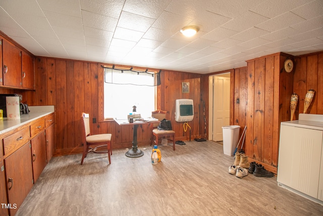 interior space with light wood-type flooring, washer / clothes dryer, wooden walls, and heating unit