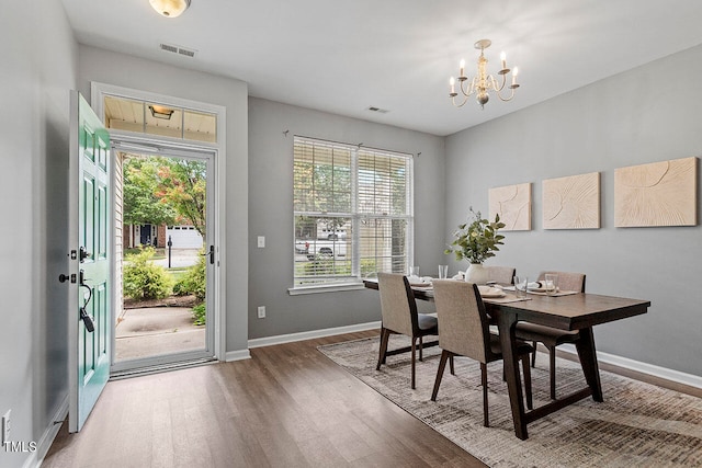 dining area with hardwood / wood-style flooring and an inviting chandelier