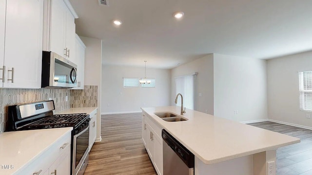 kitchen featuring a kitchen island with sink, white cabinets, sink, pendant lighting, and appliances with stainless steel finishes