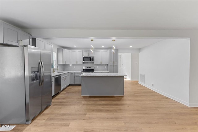 kitchen featuring gray cabinetry, appliances with stainless steel finishes, a center island, pendant lighting, and light hardwood / wood-style flooring