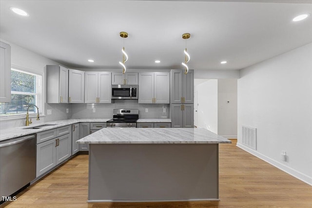 kitchen with decorative light fixtures, stainless steel appliances, sink, and gray cabinetry