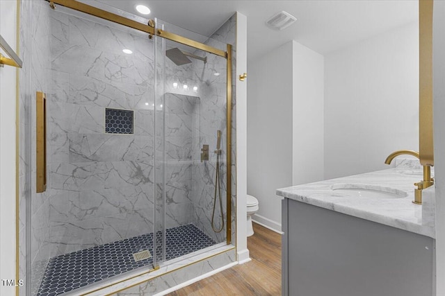 bathroom with toilet, a shower with shower door, hardwood / wood-style flooring, and vanity