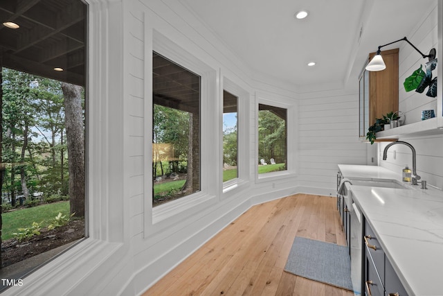 interior space with wooden walls, sink, and light wood-type flooring