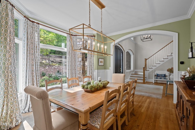 dining area with a notable chandelier, light wood-type flooring, and crown molding