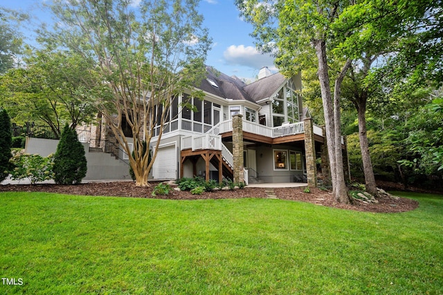 rear view of house with a garage, a yard, and a sunroom