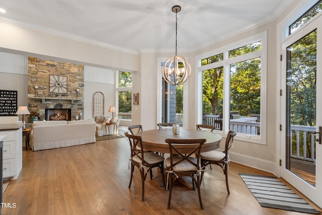 dining area featuring a fireplace, light hardwood / wood-style floors, crown molding, and an inviting chandelier