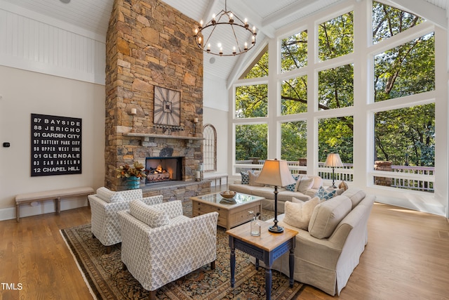 living room featuring hardwood / wood-style floors, high vaulted ceiling, and a stone fireplace